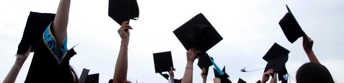 Graduates stand together, proudly holding their caps high in the air as they commemorate their graduation day.