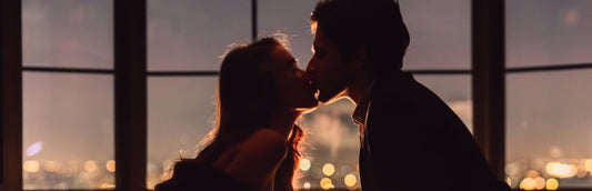 A couple Kissing in the dark with a window behind them